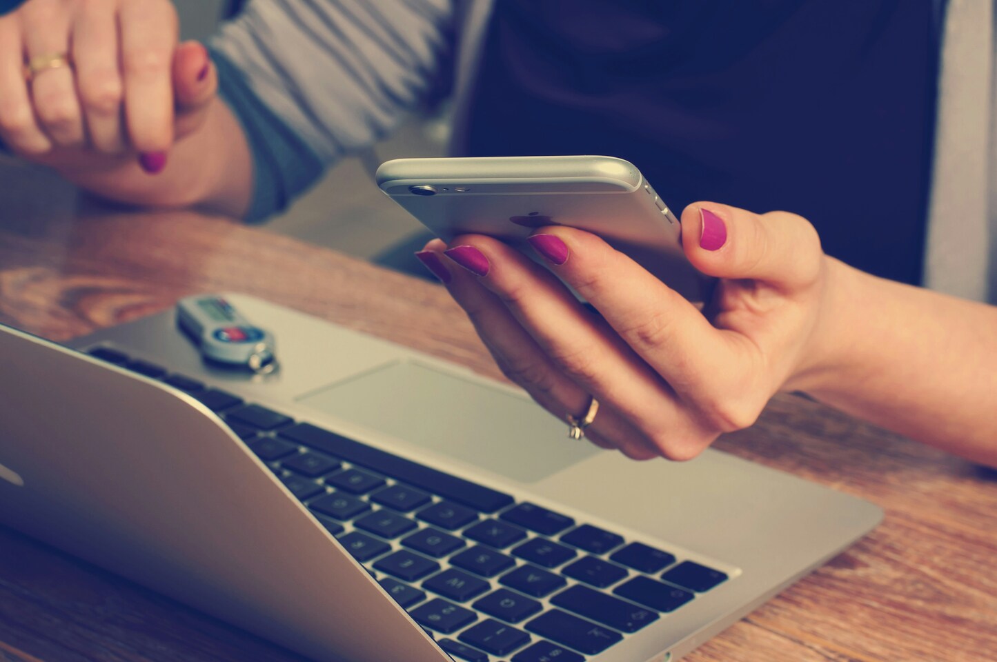 Frau recherchiert mit Smartphone und Laptop.