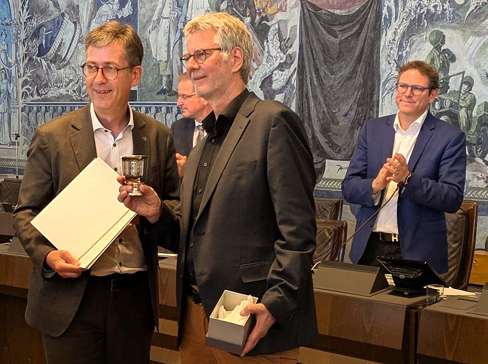 OB Christian Schuchardt ehrt Stadtrat Matthias Pliz mit dem Silbernen Ratsbecher für seine 35-jährige Stadtratstätigkeit. Im Hintergrund applaudiert 2. Bürgermeister Martin Heilig.